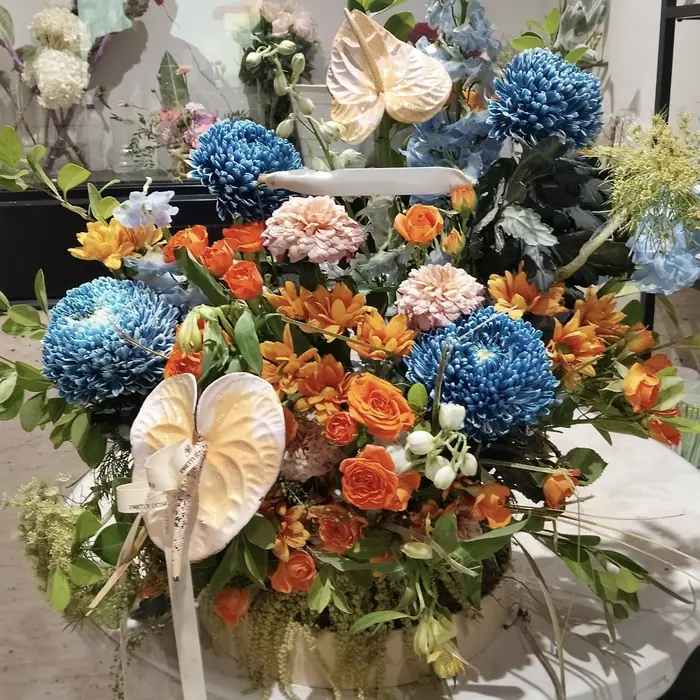 Arrangement in blue and orange with white anthurium